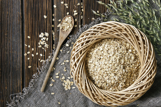 燕麦片在木盘中，木制背景围巾上的勺子特写照片图片下载