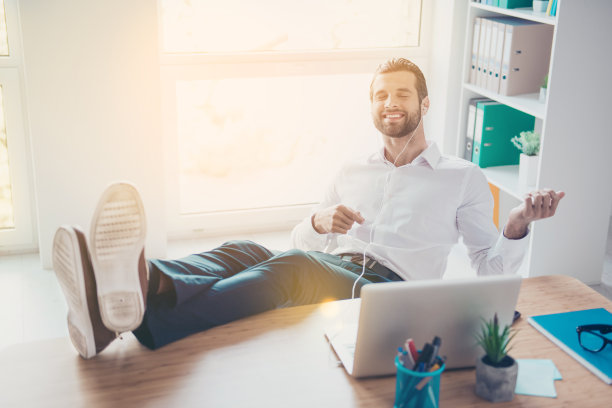 英俊的微笑年轻的商人梦想成为吉他手，享受音乐和手势像弹吉他，坐在桌子上明亮的办公室图片下载