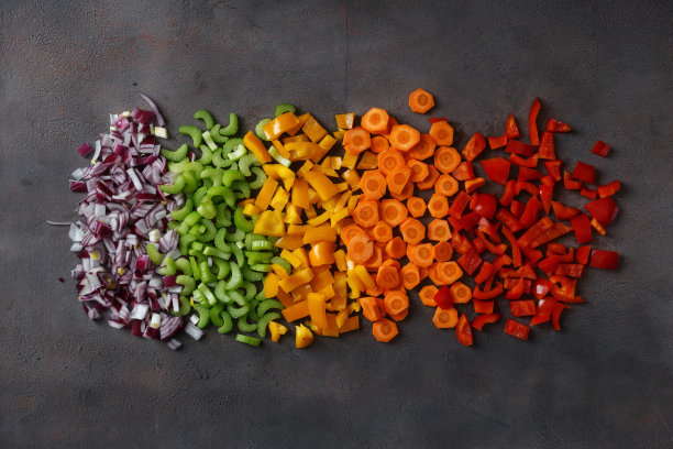 将切好的新鲜蔬菜平铺在深色的背景上。俯视图图片下载