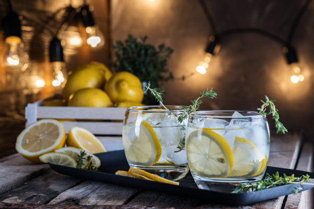 柠檬鸡尾酒加百里香和冰在黑暗的乡村背景，特写。清爽的黄色酒精鸡尾酒饮料。图片下载