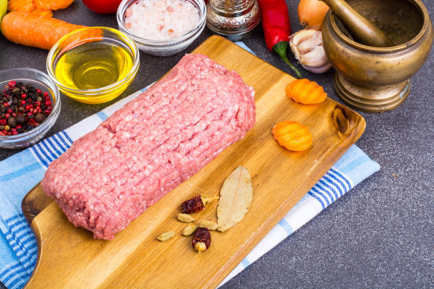 新鲜的碎肉放在木板上，加上香料，蔬菜图片下载