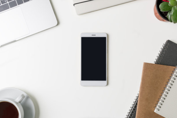 俯视图的办公室工作场所。有复印空间的白色办公桌。平躺在桌子上看笔记本电脑，眼镜，笔记本和电话。有创意的设计师的概念。图片下载