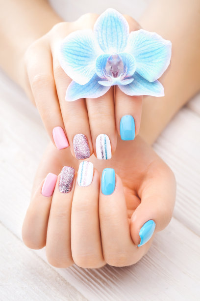 白色木桌上点缀着兰花、蜡烛和毛巾的彩色美甲。图片下载