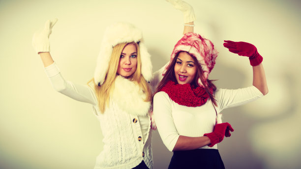 两个女孩暖和冬天的衣服玩。图片下载