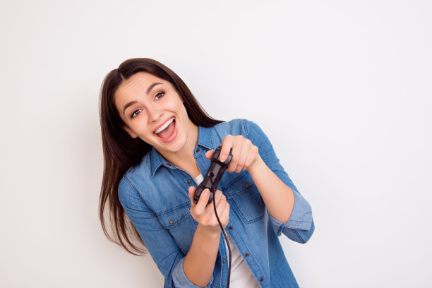 可爱的快乐微笑的年轻女子的肖像穿着牛仔裤衬衫，拿着手柄在手里和有乐趣图片下载