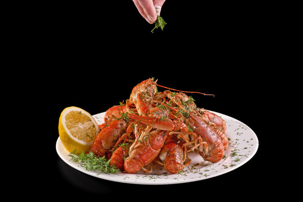 将煮熟的红色小龙虾或小龙虾放入啤酒中，在黑色的背景上撒上香草。关闭它。小龙虾派对，餐厅，咖啡馆，酒吧菜单，食物概念。副本的空间。素材图片