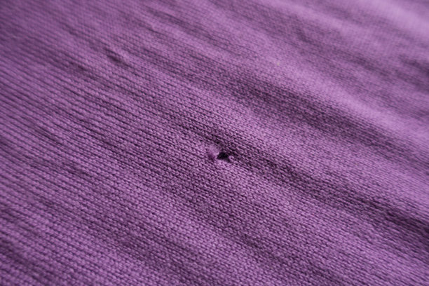 特写的小撕裂在粉红色针织织物图片下载