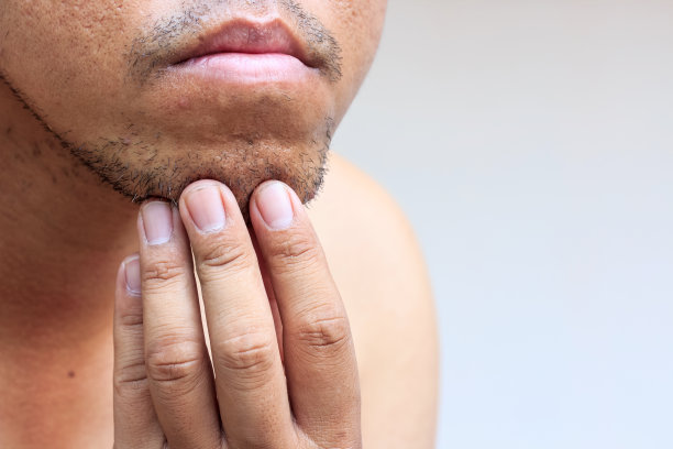 年轻的大胡子男子的特写，触摸他的白背景胡子图片下载