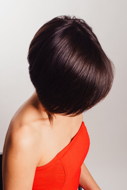 褐发女人穿着白色背景上有花的红色连衣裙图片下载