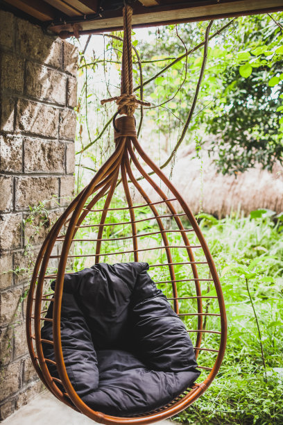 夏日花园里的藤挂柳条椅，配有黑枕图片下载