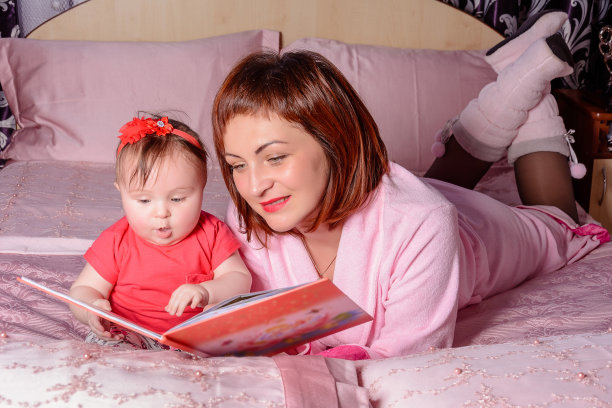 一位年轻美丽的母亲穿着粉红色的晨衣躺在床上图片下载