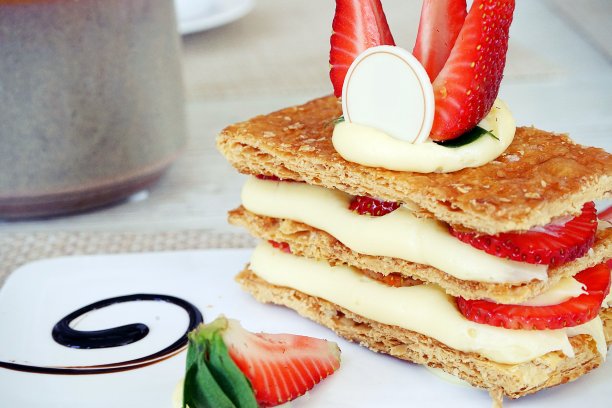 法式甜品是一种白色盘子里的法式甜品，上面是一堆派皮、奶油和新鲜草莓，再加上草莓和白巧克力。图片下载