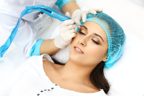 专业美容师在女人脸上纹眉。美容院永久眉妆，特写。美容应用素材图片