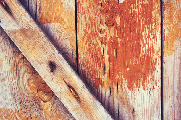 旧的木制背景漆有红色和黄色的裂缝和摩擦。素材图片