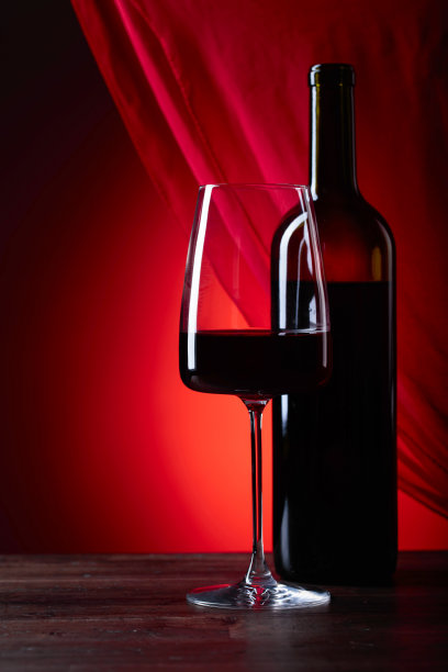 酒杯和酒瓶上的红葡萄酒在红色的背景。图片下载