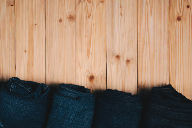 卷磨损牛仔裤或蓝色牛仔裤牛仔收集粗糙的木制桌子背景与拷贝空间，旧的时尚概念。图片下载