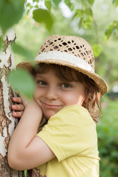 一个小女孩戴着草帽靠近白桦树，暑假图片下载