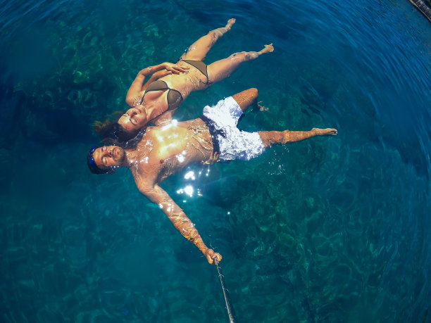 自拍与一根轻松的年轻英俊的情侣游泳在绿松石的海面上的暑假。图片下载