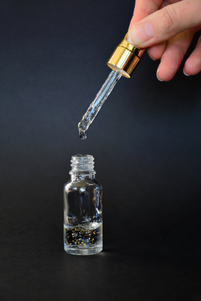 豪华的面部血清容器与滴管在黑色背景素材图片