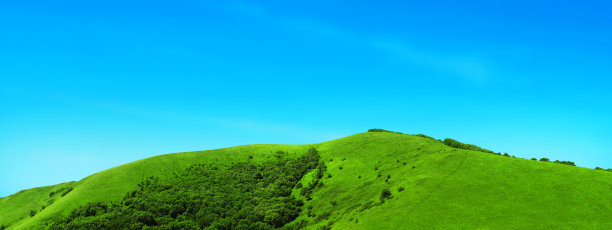全景夏日绿油油的草地和山林。美丽的风景,旅游。清新的绿色田园草地，在晴朗的一天，无云的蓝天。风景如画，乡间小路穿过群山图片下载