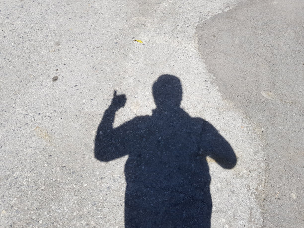 商人的影子举起的手在水泥地板上显示拇指符号。商业成功的概念。图片下载