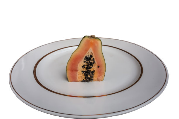 半只新鲜多汁的木瓜放在镶金边的白色盘子里图片下载