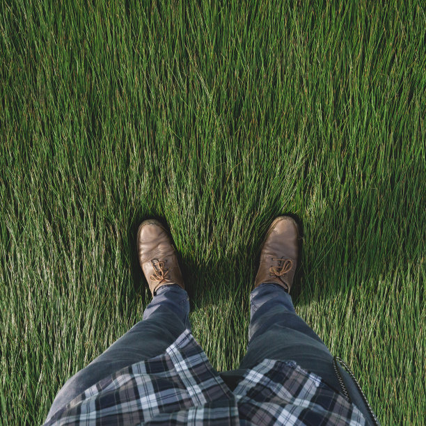 一个穿着泥鞋站在毛茸茸的草地上的男人图片下载
