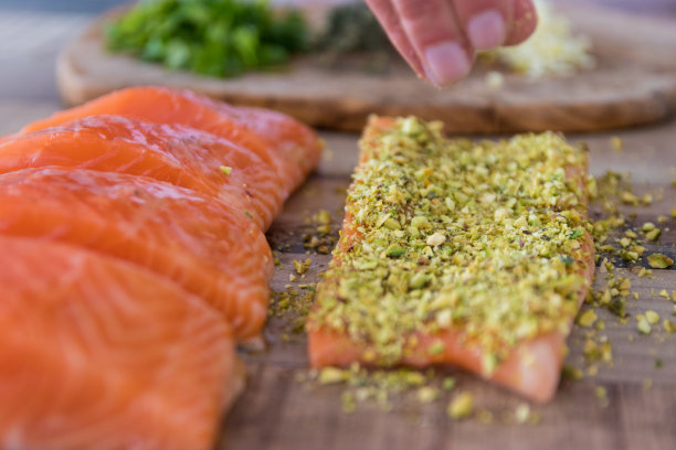 用手把开心果撒在生鲑鱼上素材图片