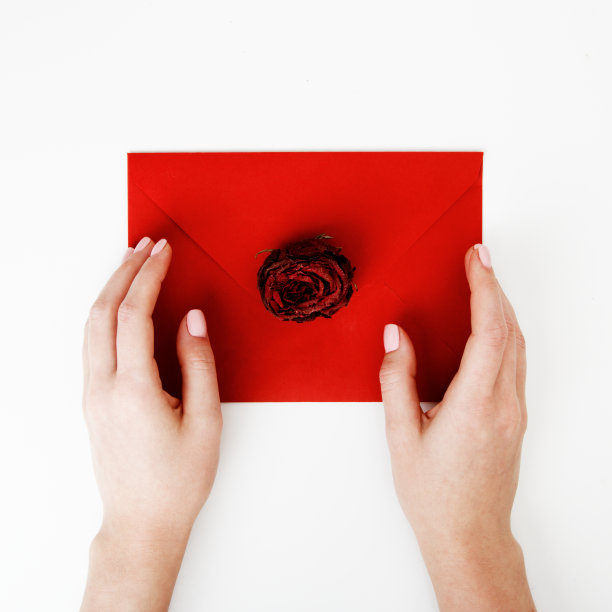 极简时尚和美丽的照片。一封装在红信封里的玫瑰情书。女人手里拿着一封情书。情人节的概念。浪漫的摄影。2月14日图片下载