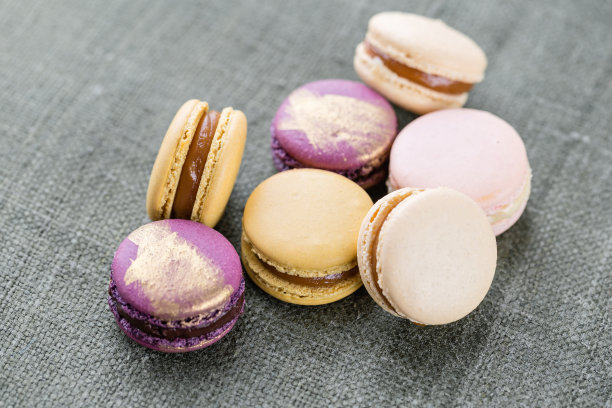 特写:白色木桌上五颜六色的法国或意大利马卡龙。马卡龙是法国甜点，配茶或咖啡。壁纸、水平照片图片下载