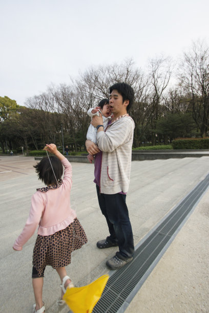 父亲抱着孩子和女儿在外面玩耍图片下载