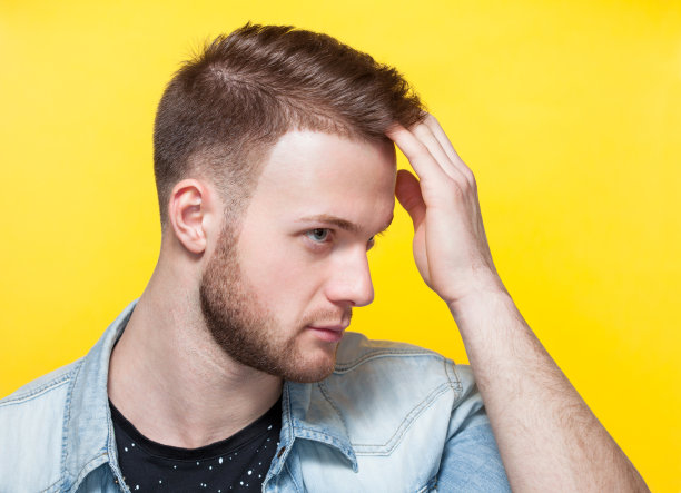 黄色背景上的理发店里一个英俊的年轻人的肖像。图片下载