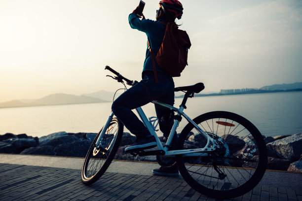 人们在海边骑山地车的时候用手机拍照图片下载
