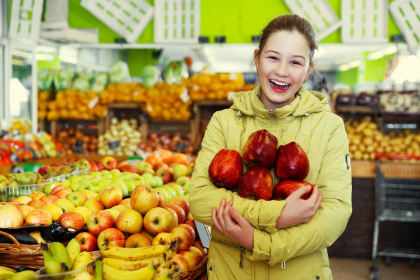水果市场里拿着红苹果的女孩图片下载