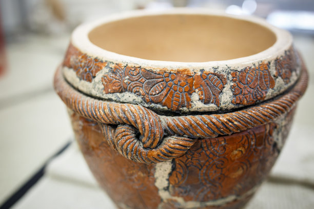 白色桌布上放着一只棕色的旧陶瓷锅素材图片