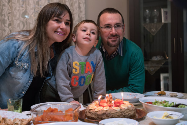 孩子和她的父母吹灭生日蛋糕上的蜡烛图片下载