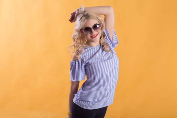 黄色背景上那位戴着墨镜的漂亮年轻女子的肖像图片下载