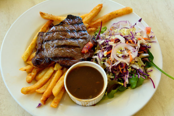 一盘牛排配沙拉、炸土豆和蘑菇酱。图片下载
