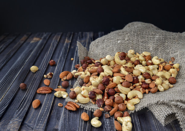 混合杏仁，腰果，澳洲坚果，花生，核桃，山核桃，松子，开心果在木背景图片下载