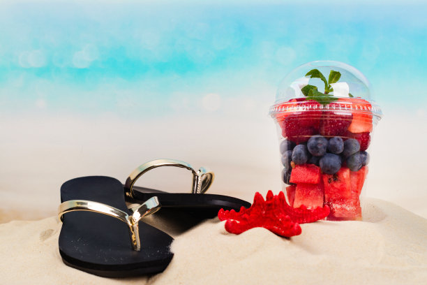 人字拖和塑料杯，上面放着海边切好的水果和浆果图片下载