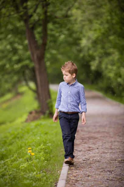 可爱的小男孩走在夏日公园的小路上。夏季森林背景。学校里男孩的户外活动。图片下载