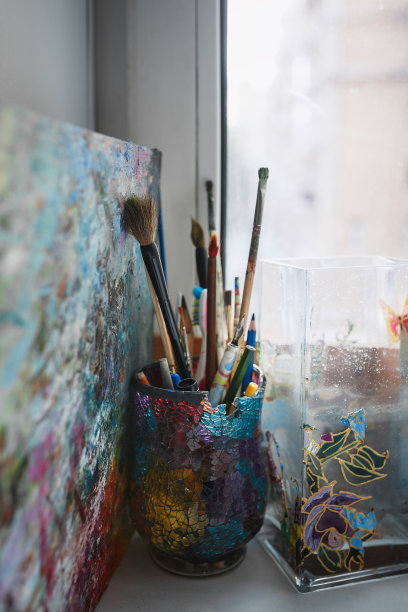 各种艺术家的画笔和铅笔都是在一个美丽的玻璃，彩色玻璃。有一张焦距不准的照片。垂直的照片。图片下载