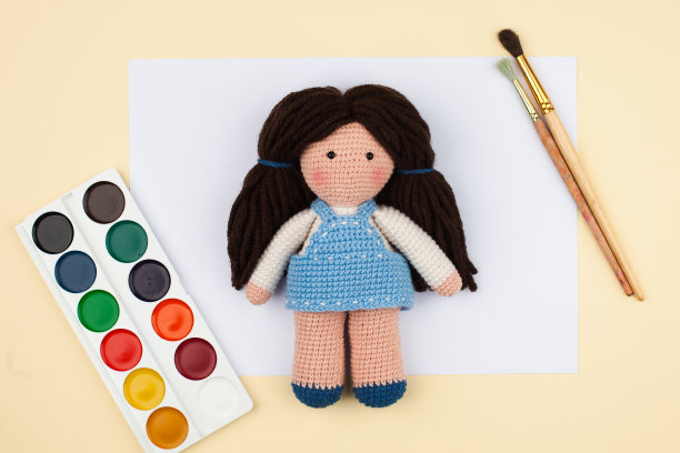 阿米古米娃娃以棕色的头发，水彩画，纸笔在浅黄色的背景上，假日的概念，儿童的创造力和发展图片下载