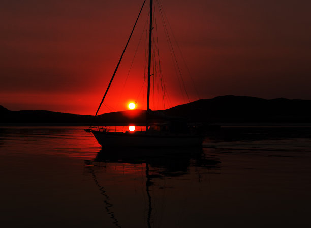 深红的海景日出与游艇剪影。图片下载