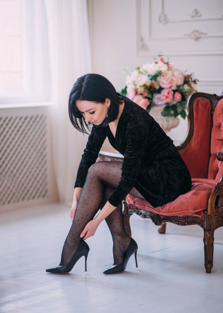 女人坐在扶手椅上，穿着紧身裤摸着自己的腿图片下载