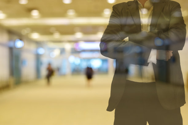 背景模糊，色调温暖的早晨。楼里有人。前景是一个穿着黑色西装的男人。图片下载