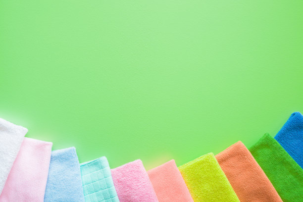 色彩鲜艳，干燥的超细纤维布，用于厨房，浴室和其他房间的不同表面清洁。绿色背景上文字或标志的空白位置。清洁服务理念。定期清理。图片下载