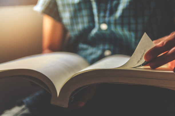 穿绿格子衬衫的男人。坐在椅子上，打开书看书。日落和instagram风格滤镜照片复古色调，选择性聚焦图片下载