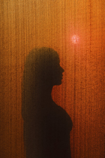 《日落时窗帘后的女人图片下载