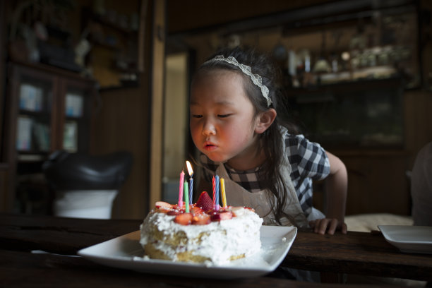 小女孩吹灭生日蛋糕蜡烛素材图片